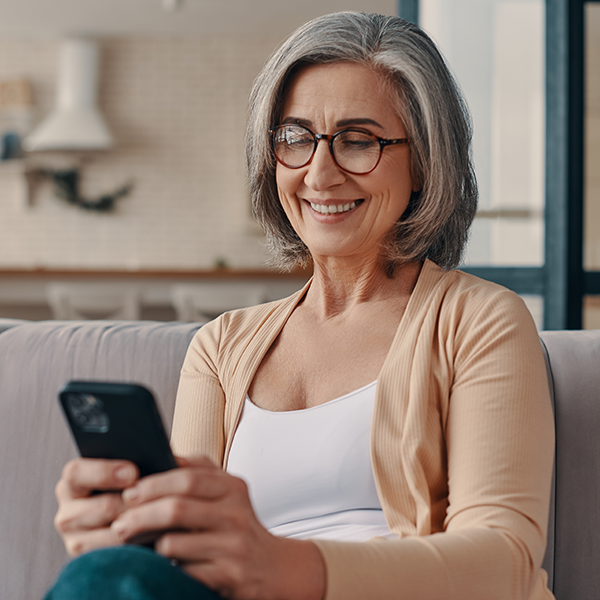 An elderly woman smiling while holding a phone