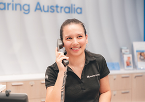 A Hearing Australia Front of House team member on a call with clients, smiling and friendly