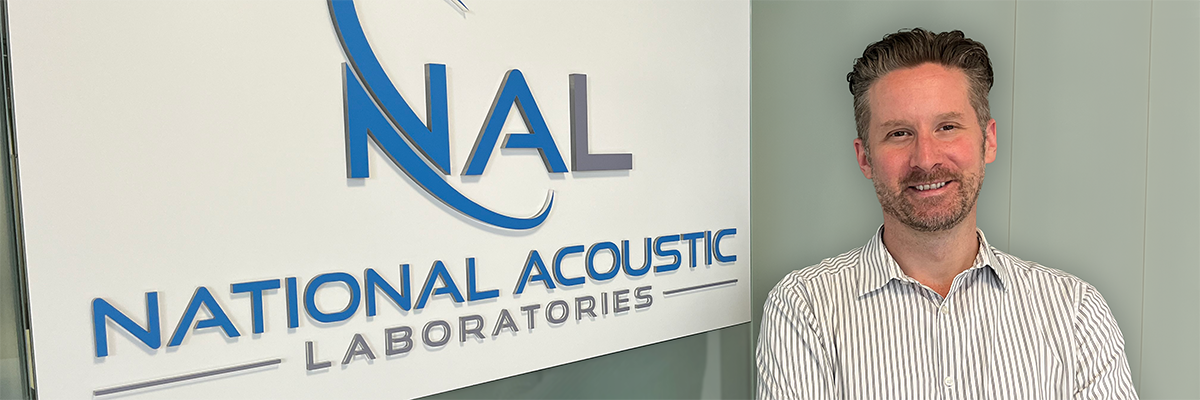 Matt, Research Audiologist at NAL, standing with NAL background