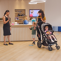 Hearing Australia audiologist waving goodbye to a mother and child with a warm smile