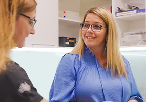 Two Hearing Australia colleagues having a friendly discussion together in the workplace